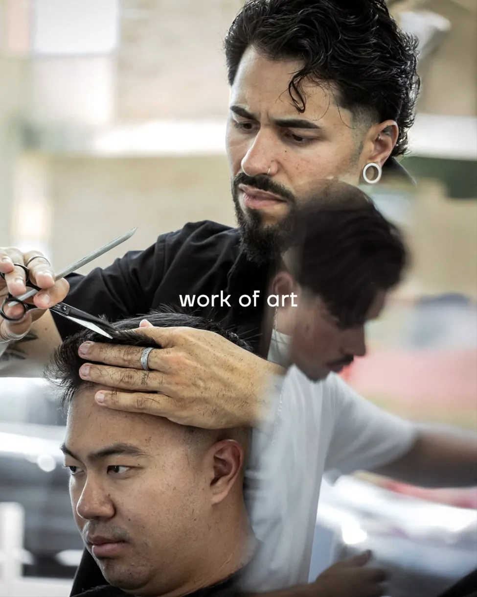 Rogério cutting a client’s hair, with another barber working behind him